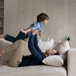 51789156-dad-lying-on-couch-lifts-on-outstretched-hands-little-son